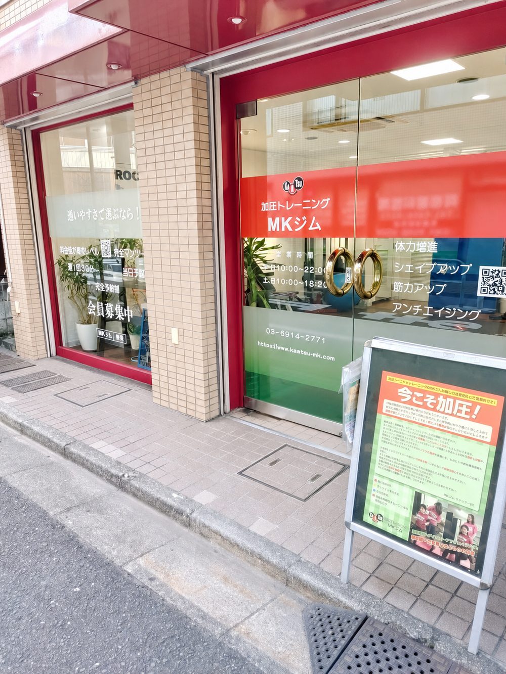 赤い外装に加圧トレーニングの看板を掲げたMKジム大山店の店舗外観